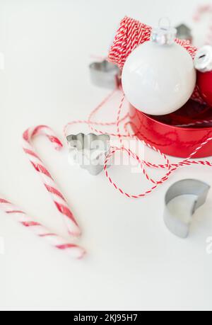 Les bonbons de Noël, ainsi que les emporte-pièces, les décorations de Noël et le fil rouge pour l'emballage des cadeaux, reposent sur une table blanche. Mise au point sélective, bruit. CH Banque D'Images