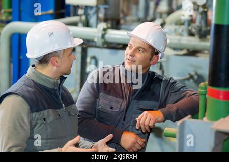 un superviseur masculin avec un employé discutant en usine Banque D'Images