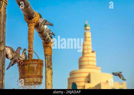 Gros plan de pigeons à l'ancienne fontaine de puits, point de repère emblématique au milieu de Souq Waqif dans le centre-ville de Doha, Qatar. Moyen-Orient, péninsule arabique. Ensoleillé Banque D'Images