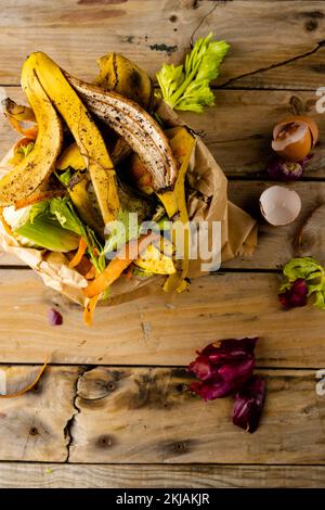 Charge verticale des déchets de fruits et légumes organiques qui se répandent dans la poubelle de compostage de la cuisine Banque D'Images