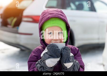 Portrait d'un mignon adorable beau caucasien petit enfant garçon fille profiter de boire chaud thé ou chocolat cacao marche à l'extérieur lumineux ensoleillé Banque D'Images