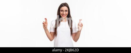 Portrait de la taille vers le haut de la fille optimiste croient que les rêves deviennent réalité, portez des lunettes et un t-shirt, crossets de la chance, faites le souhait, priant et Banque D'Images