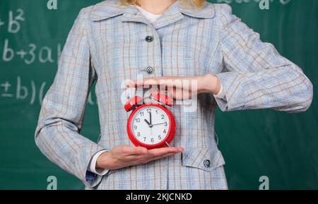 Concept de discipline scolaire. Calendrier et régime. Réveil en gros plan entre les mains des femmes. Attributs des enseignants. Réveil entre les mains d'un enseignant ou d'un éducateur Banque D'Images