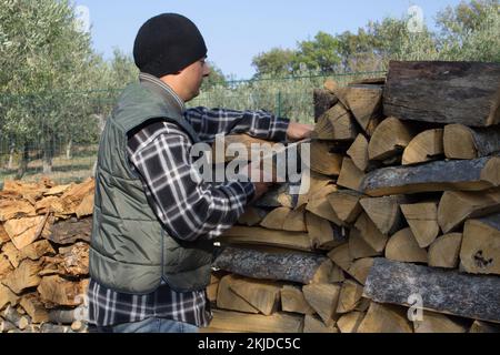 Un homme qui fait le plein de bois en prévision du froid et de l'hiver. Référence au chauffage de la maison avec du bois de chauffage. Économies sur le coût du chauffage domestique. Banque D'Images