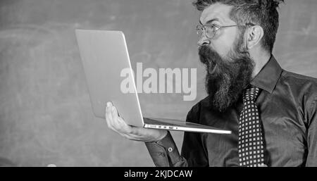 Des informations choquantes. Hipster professeur porter lunettes et cravate tient ordinateur portable surfer sur Internet. Des nouvelles choquantes. Professeur barbu homme choqué avec Banque D'Images