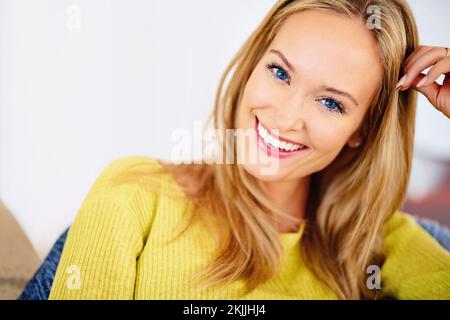 S'asseoir sur le canapé. Portrait court d'une belle jeune femme qui se détend à la maison. Banque D'Images