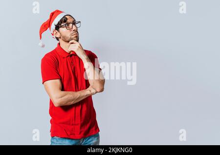 Un Noël bien pensé qui regarde de côté. Noël beau gars avec le visage réfléchi isolé. Homme attentionné en vêtements de noël avec main sur le menton. T Banque D'Images