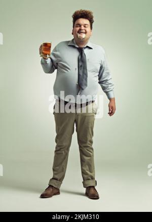 La bière est bonne. un homme en surpoids qui célèbre tout en tenant une pinte de bière. Banque D'Images