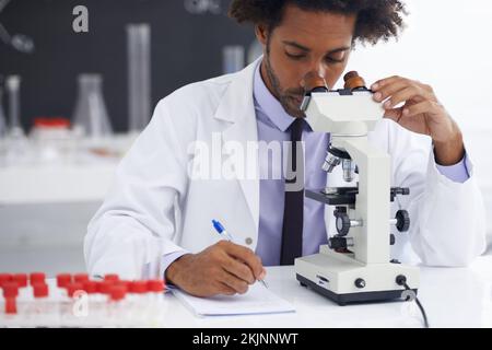 Zoom avant sur un virus. un biologiste mâle regardant une lame de verre à travers un microscope. Banque D'Images