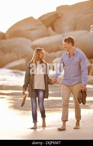 Promenades au coucher du soleil. un jeune couple heureux profitant d'une promenade romantique sur la plage au coucher du soleil. Banque D'Images