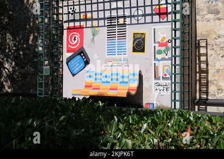 Un banc avec quelques œuvres d'art de rue sur le mur derrière dans le parc Coulee verte Rene-Dumont à Paris, France Banque D'Images