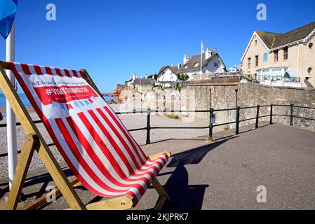 Vue sur les maisons traditionnelles en chaume donnant sur la plage à l'extrémité ouest de la ville avec un grand transat en premier plan, Sidmouth, Royaume-Uni. Banque D'Images