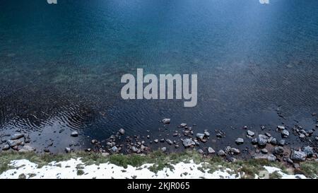Czarny Staw Pod Rysamy ou lac Black Pond près de la cabane de montagne Morskie Oko Snowy dans les montagnes polonaises de Tatry, vue sur les drones, Zakopane, Pologne. Vue aérienne prise de magnifiques collines verdoyantes et montagnes dans des nuages sombres et reflet sur le lac Morskie Oko. Destination touristique de voyage Banque D'Images