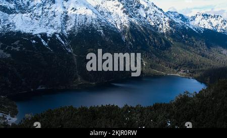 Czarny Staw Pod Rysamy ou lac Black Pond près de la cabane de montagne Morskie Oko Snowy dans les montagnes polonaises de Tatry, vue sur les drones, Zakopane, Pologne. Vue aérienne prise de magnifiques collines verdoyantes et montagnes dans des nuages sombres et reflet sur le lac Morskie Oko. Destination touristique de voyage Banque D'Images