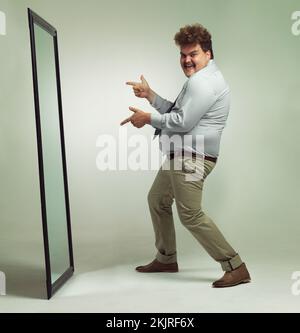 La messagerie instantanée a l'air géniale. un homme enthousiaste en surpoids qui célèbre tout en regardant dans un miroir. Banque D'Images