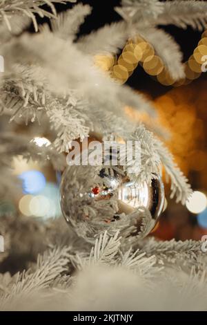 Boule de Noël argentée à miroir brillant à l'extérieur sur un arbre blanc Banque D'Images