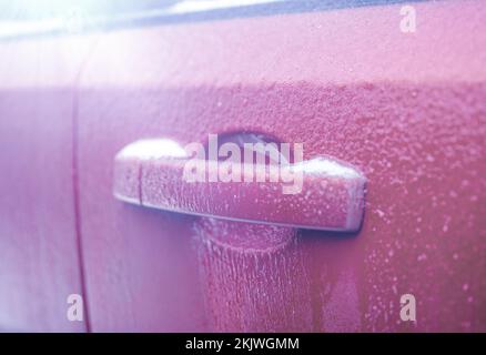 Poignée de porte de voiture gelée. Gros plan de la poignée et de la serrure de la porte de voiture recouvertes de glace pendant la tempête d'hiver. Concept de préparation et de sécurité à la conduite en hiver Banque D'Images