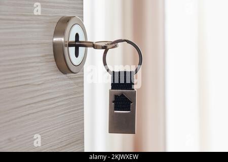 Clé avec porte-clés dans la serrure de porte. Porte ouverte de la chambre. Concept immobilier Banque D'Images