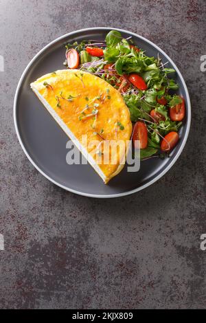 Omelette du Poulard français aérée servie avec une salade fraîche sur une assiette sur la table. Vue verticale du dessus Banque D'Images