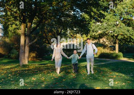 une mère de famille et 2 fils s'amusent, s'amusent dans le parc et sautent. Fils, enfants, maman, courir, jouer, réjouissez-vous, profitez de la nature en été. Famille Banque D'Images