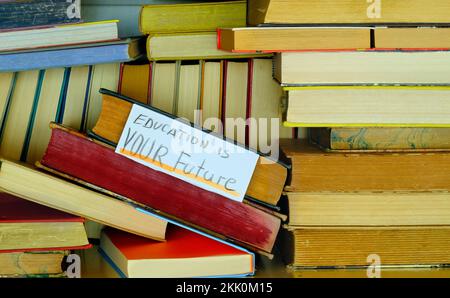 Pile de livres hardback dans une bibliothèque avec l'éducation est votre futur signe.apprentissage, éducation, connaissance, retour à l'école concept. Banque D'Images