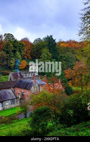 Spectaculaire couleur d'automne sur les arbres boisés, une cheminée à fumer et l'église paroissiale de Stourhead Gardens, Wiltshire, Angleterre, Royaume-Uni Banque D'Images