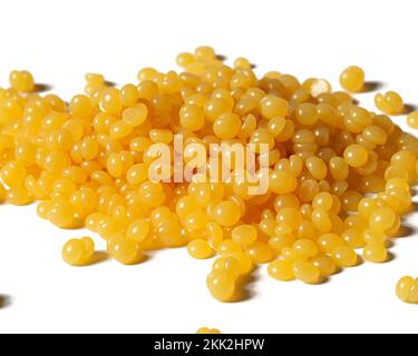 Pile de perles de cire d'abeille jaune naturelle isolées sur un fond blanc Banque D'Images