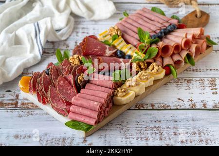 Assiette de viande fumée froide sur plancher en bois. Plaque en bois de platère de jeu d'antipasti. Viande fumée froide avec prosciutto, salami, bacon, côtelette de veau Banque D'Images