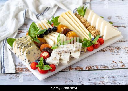 Assiette de fromages mélangés sur parquet. Délicieux assortiment de fromages. Camembert, Brie, parmesan, chèvre Banque D'Images
