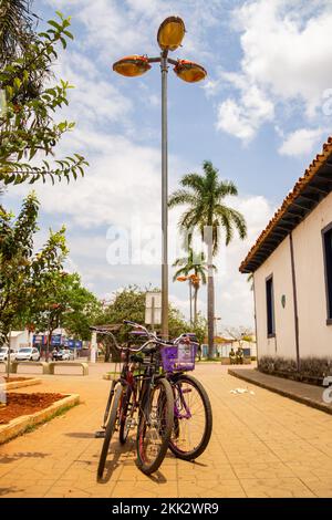 Aparecida de Goias, Brésil – 23 octobre 2022 : trois bicyclettes attachées au poteau avec une chaîne sur une place de ville. Banque D'Images