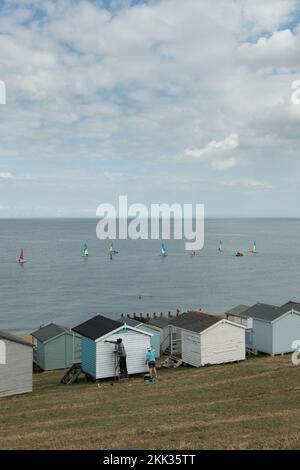 Prendre le temps de peindre et de rénover une cabane blanche sur la plage avec une nouvelle peinture sur une journée de mer calme à Whitstable parmi des huttes multicolores, belle vue sur la mer Banque D'Images