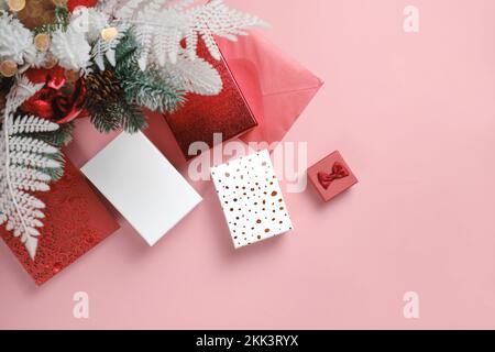 Cadeaux sous brunches d'arbre de Noël décorées. Cases blanches et rouges sur rose. Bannière d'espace de copie prête, vue de dessus. Carte de fête avec cadeaux Banque D'Images