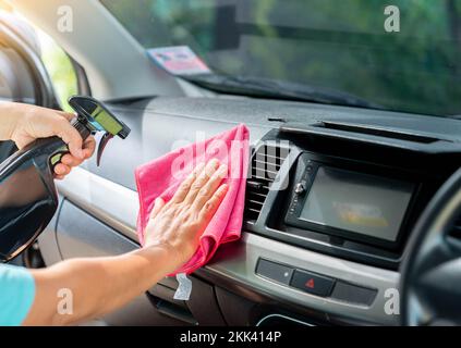 Chiffon en microfibre rose pour nettoyer l'intérieur de la voiture et pulvériser du liquide de désinfection. Détails de voiture. Banque D'Images