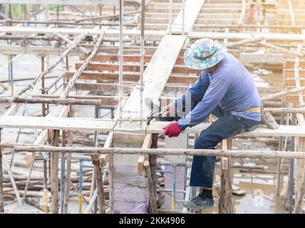 Le travailleur a frappé les clous au deuxième étage pour les travaux de coffrage d'instruction sur le chantier. Banque D'Images