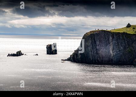 Groupe de touristes se tenant sur une falaise lointaine surplombant l'océan Atlantique sur le sentier de randonnée Skerwink à Terre-Neuve-et-Labrador. Banque D'Images