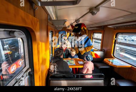 Oberwiesenthal, Allemagne. 25th novembre 2022. Les familles jouent à divers jeux de dés lors de la mise en service de la nouvelle voiture de jeu de la Fichtelbergbahn. C'est la première voiture de jeu sur un chemin de fer à voie étroite saxonne. La Sächsische Dampfeisenbahngesellschaft (SDG) a investi 11 500 euros dans la conversion et la conception de la voiture. Credit: Kristin Schmidt/dpa/Alay Live News Banque D'Images