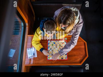 Oberwiesenthal, Allemagne. 25th novembre 2022. Charly, six ans, et sa sœur Julia jouent ensemble un jeu de dés lors de la mise en service de la nouvelle voiture de jeu de Fichtelbergbahn. C'est la première voiture de jeu sur un chemin de fer à voie étroite saxonne. La Sächsische Dampfeisenbahngesellschaft (SDG) a investi 11 500 euros dans la conversion et la conception de la voiture. Credit: Kristin Schmidt/dpa/Alay Live News Banque D'Images