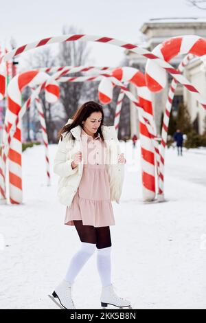 La jeune femme fait du patinage en plein air en hiver parmi les décorations de Noël. Bâtonnets de Noël au caramel. Ambiance festive Banque D'Images