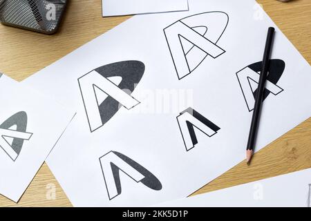 Un graphiste développe un logo pour une marque. L'illustrateur dessine des esquisses sur du papier. Banque D'Images