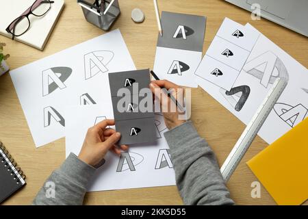 Un graphiste développe un logo pour une marque. L'illustrateur dessine des esquisses sur du papier. Banque D'Images