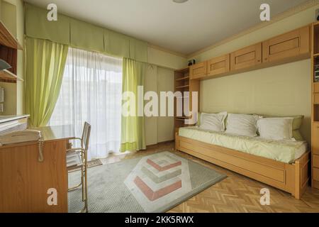 Chambre jeunesse avec mobilier en bois clair de 90s po, lit pliant et bureau assorti avec chaise en métal doré Banque D'Images