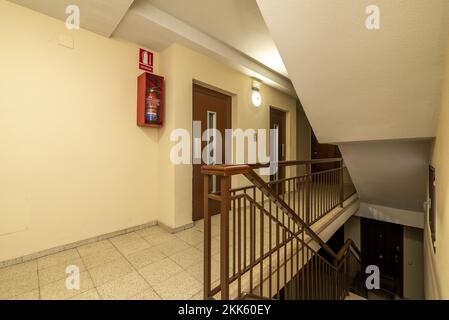 Atterrissage d'une maison d'appartement résidentielle avec un escalier avec sol en terrazzo clair, des rampes en métal peintes en rouge et des ascenseurs doubles Banque D'Images