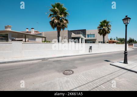 Une rue dans une urbanisation avec une traversée courbée de zèbre et des palmiers Banque D'Images