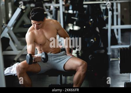 Entraînement de jeune homme asiatique, levage avec haltères pour construire le muscle dans la salle de gym. Banque D'Images
