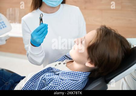 Boy regarde un outil spécial pour l'extraction des dents Banque D'Images
