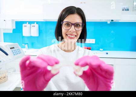 Femme agréable orthodontiste tient dans les mains le protège-bouche aligne la forme des dents Banque D'Images