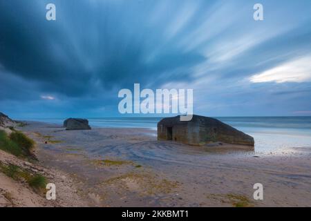 Un paysage nuageux sur un bunker abandonné sur une côte sablonneuse Banque D'Images