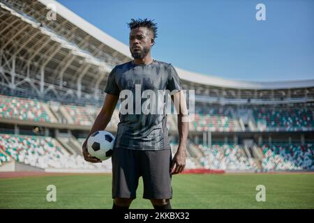 Portrait intense d'un joueur de football tenant le ballon dans le stade Banque D'Images