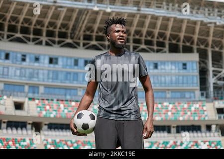 joueur de football noir confiant tenant le ballon dans la main au stade Banque D'Images