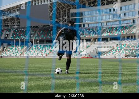 Un jeune afro-américain tenant le ballon contre le filet de but du football Banque D'Images